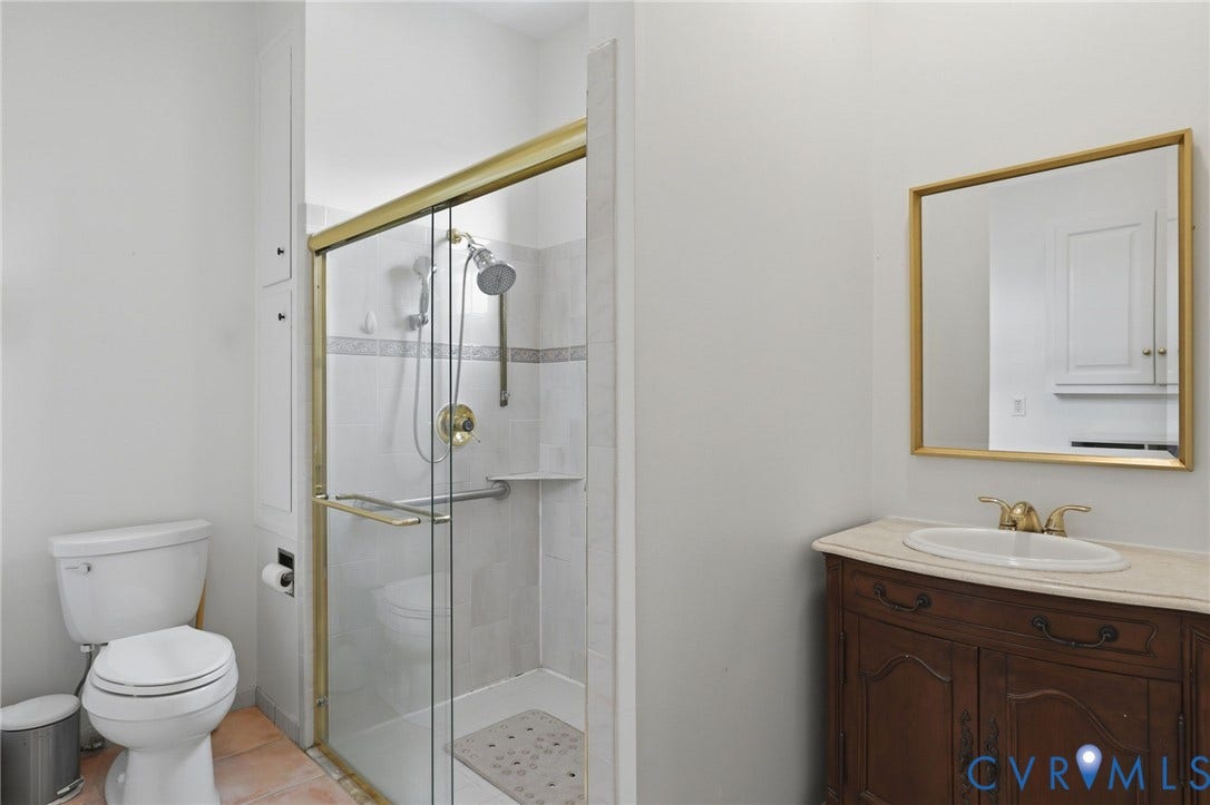 404 N Shields Avenue, Richmond, VA 23220 Bathroom featuring a glass-enclosed shower with gold-finish hardware, built-in shower niche, and white tiled walls