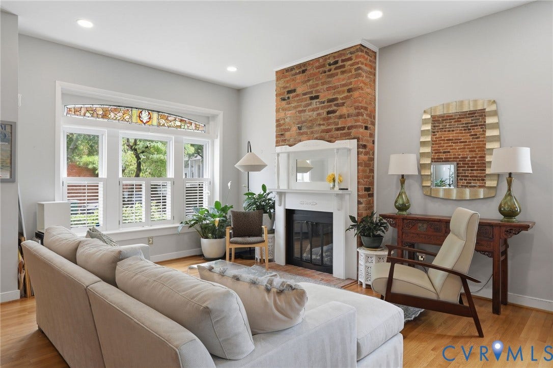 404 N Shields Avenue, Richmond, VA 23220 Living area featuring hardwood flooring, a brick accent wall with a fireplace, recessed lighting, and a large window with stained glass detail and plantation shutters