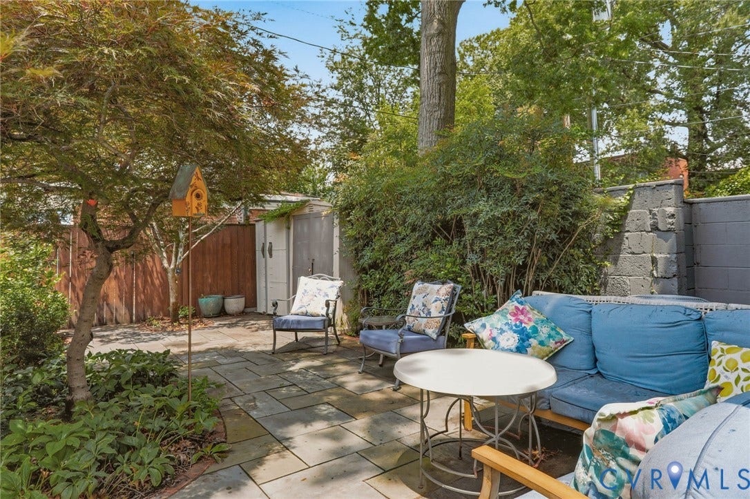 404 N Shields Avenue, Richmond, VA 23220 Spacious outdoor patio featuring flagstone paving, mature perimeter landscaping, a privacy fence, and a garden shed