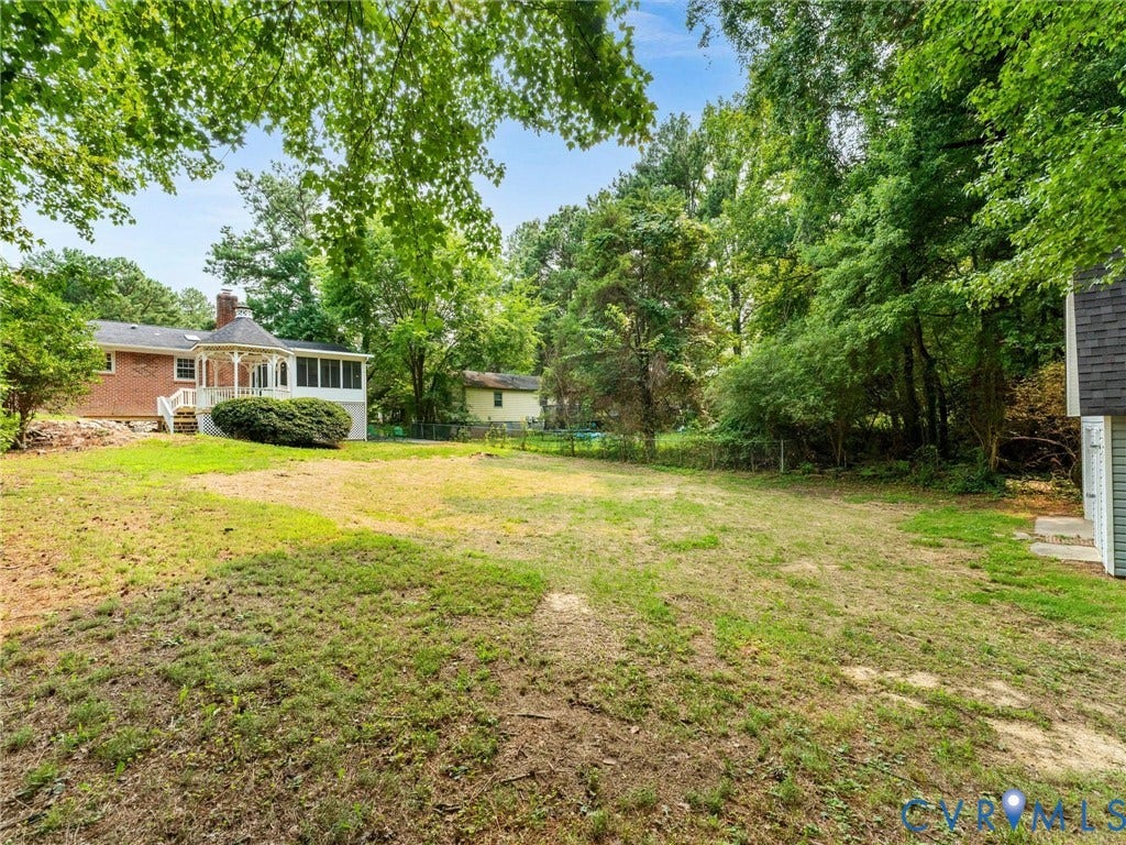 10400 Claybar Trail, Chesterfield, VA 23236 Spacious rear yard with mature perimeter trees, featuring a brick exterior, screened porch, and a white gazebo with decorative railings