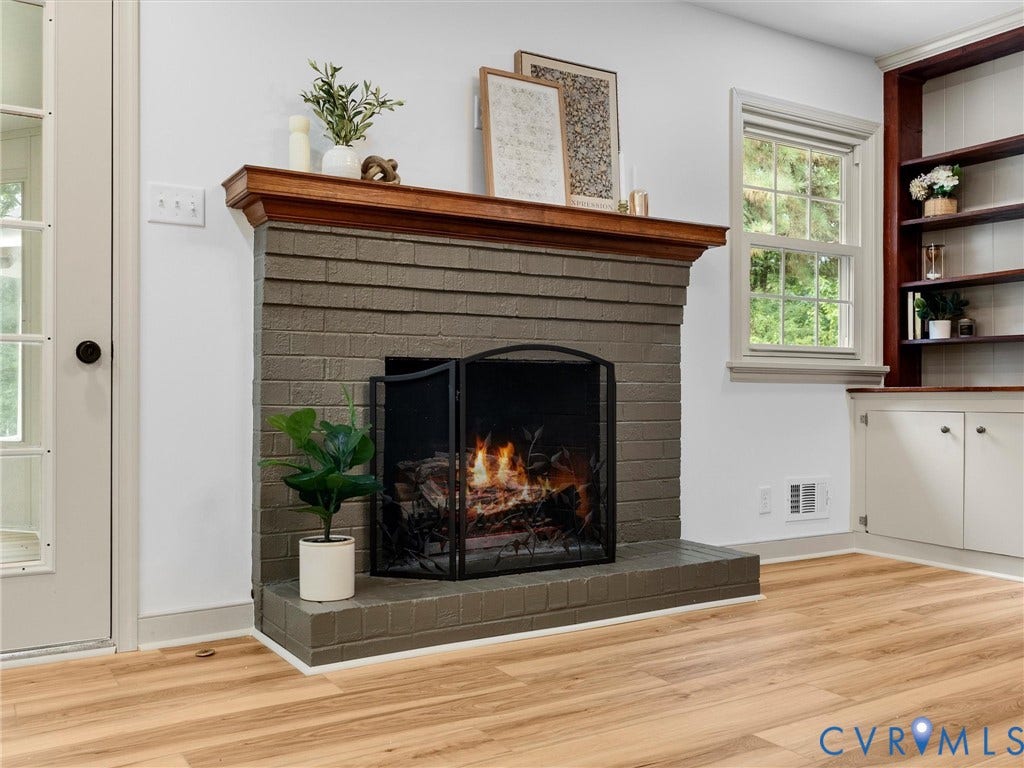 10400 Claybar Trail, Chesterfield, VA 23236 Brick fireplace with a substantial wood mantel, wood-finish flooring, built-in shelving, and a double-hung window