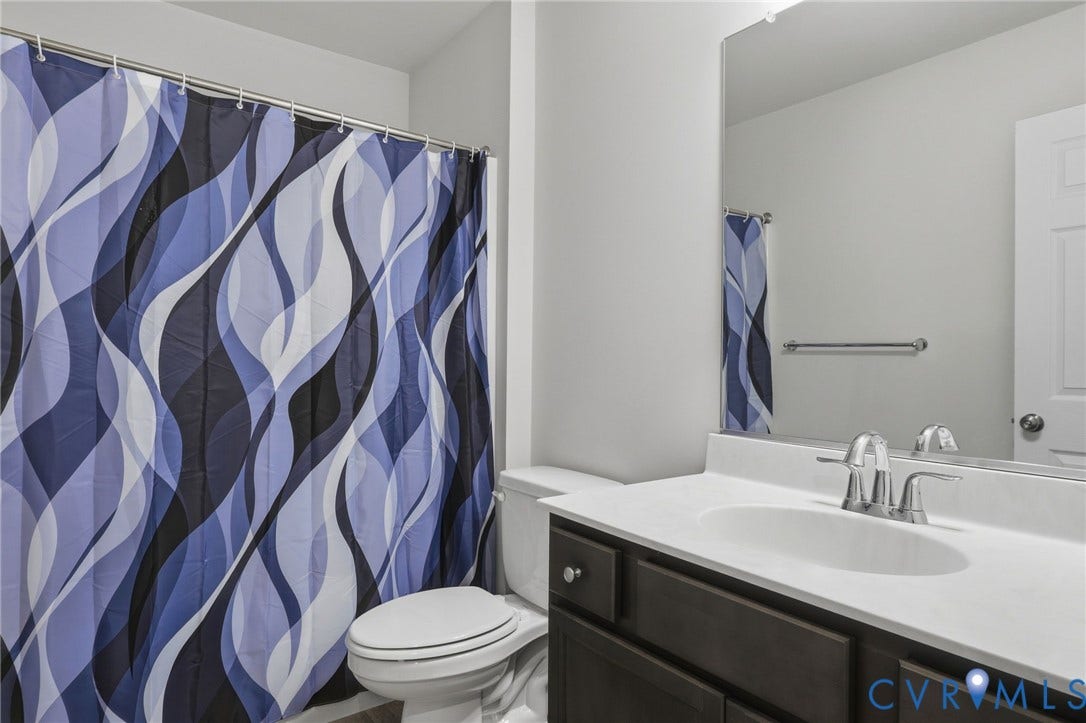 6544 Bolles Landing Court, Chester, VA 23831 Bathroom featuring a dark wood-finish vanity with a white countertop and undermount sink, a large wall-mounted mirror, and a toilet