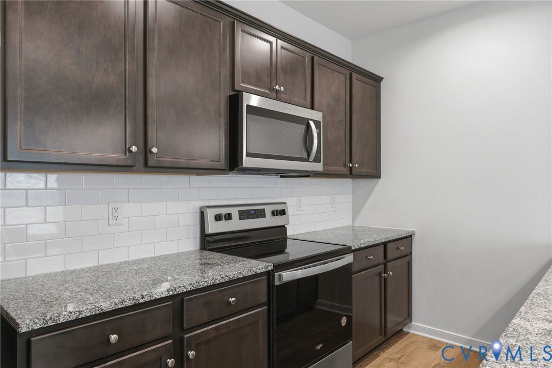 6544 Bolles Landing Court, Chester, VA 23831 Kitchen featuring dark wood-finish cabinetry, granite countertops, white subway tile backsplash, stainless steel microwave, and stainless steel electric range