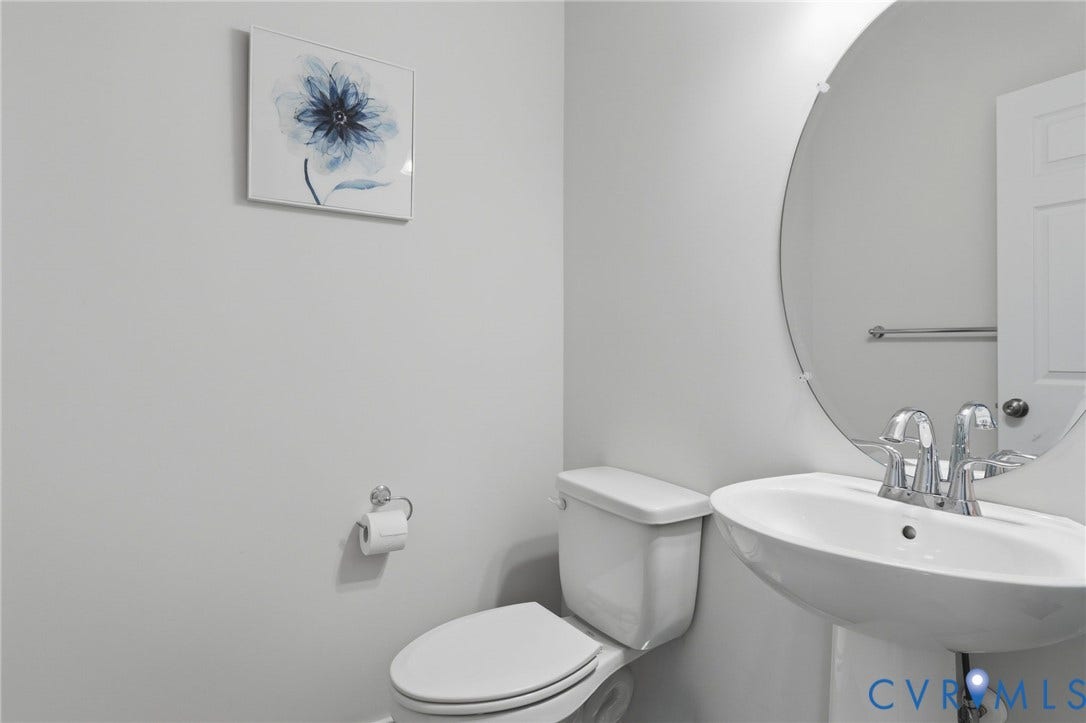 6544 Bolles Landing Court, Chester, VA 23831 Pedestal sink with chrome faucet, circular mirror, and white toilet