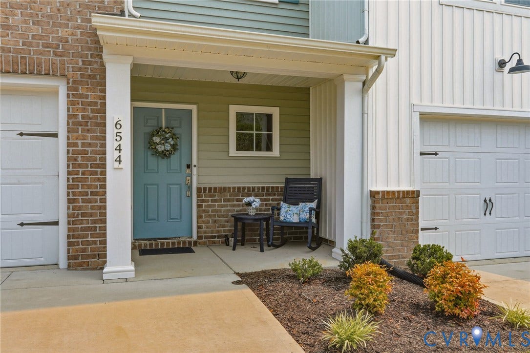 6544 Bolles Landing Court, Chester, VA 23831 Covered front entry featuring a blue door with transom window, brick facade, white siding, and a single-car garage
