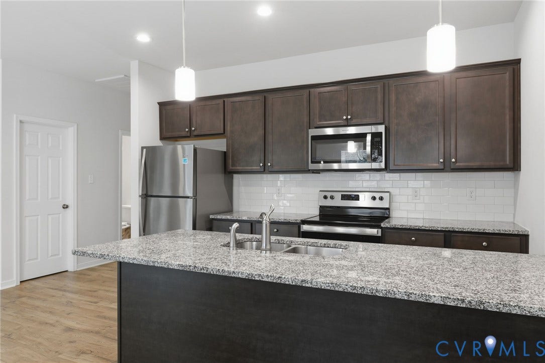 6544 Bolles Landing Court, Chester, VA 23831 Kitchen island featuring a double basin sink and a speckled countertop