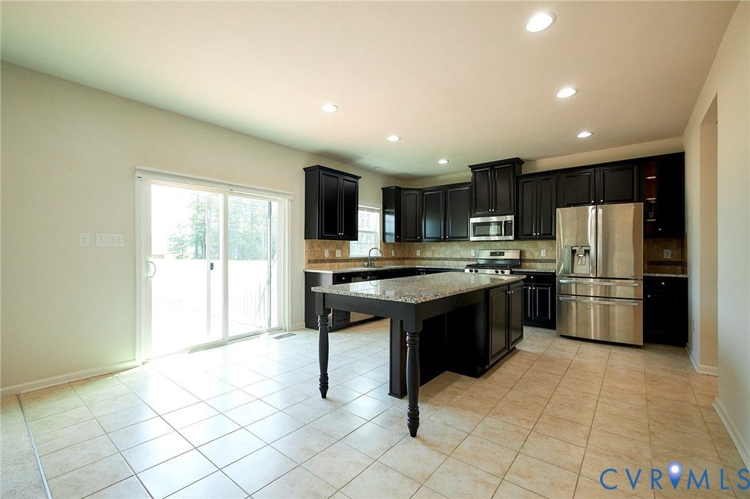 4535 Paxton Glen Court, 3W120, Glen Allen, VA 23059 Kitchen featuring dark wood cabinetry, stainless steel appliances, a center island with a stone countertop, and tile flooring