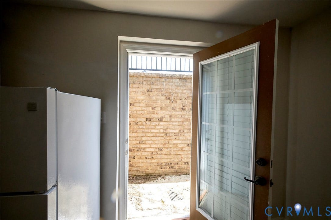 4535 Paxton Glen Court, 3W120, Glen Allen, VA 23059 Exterior door with integrated privacy blinds and dark hardware, opening to a brick-paved outdoor space with a metal fence