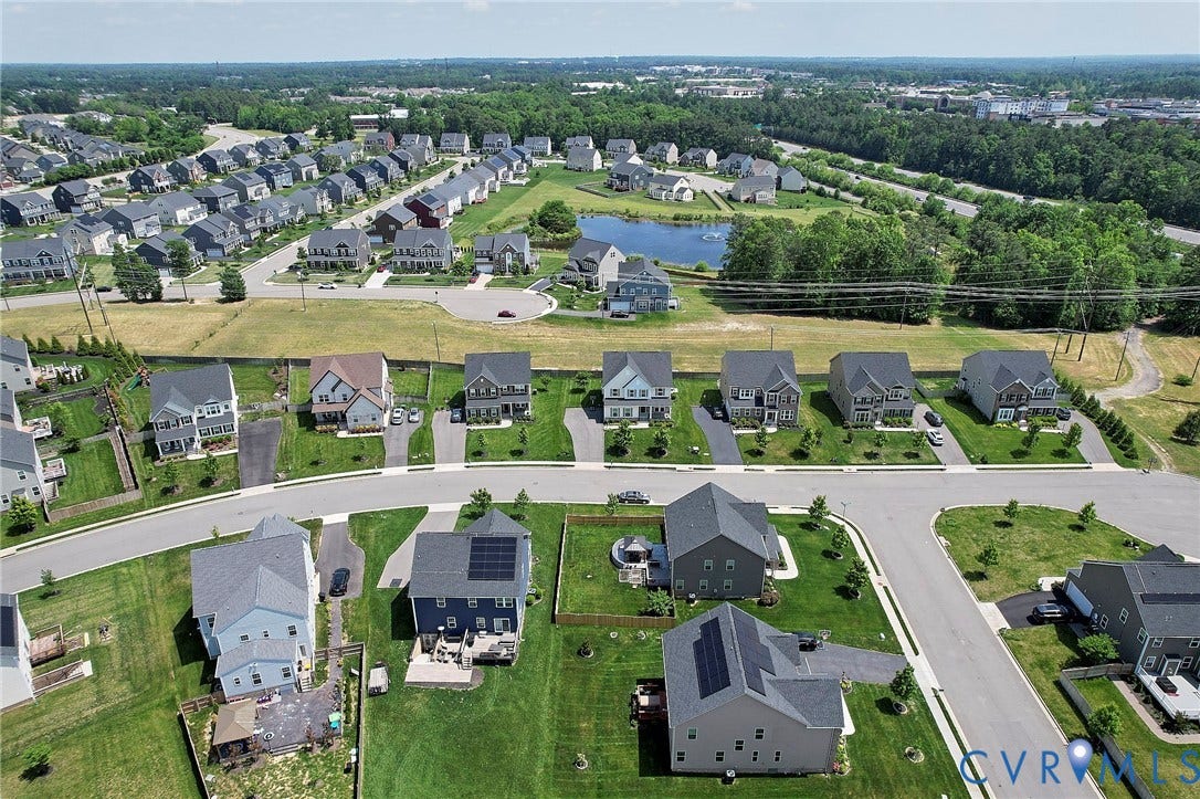 4535 Paxton Glen Court, 3W120, Glen Allen, VA 23059 Aerial perspective showcasing a residential community with diverse single-family homes, manicured green spaces, and a central pond feature