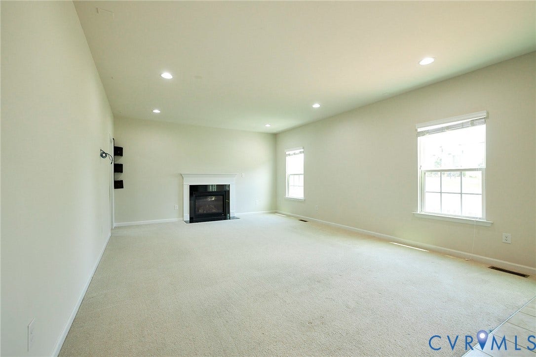 4535 Paxton Glen Court, 3W120, Glen Allen, VA 23059 Spacious room featuring a fireplace with a white mantel, recessed lighting, two windows with blinds, and light-colored carpeting