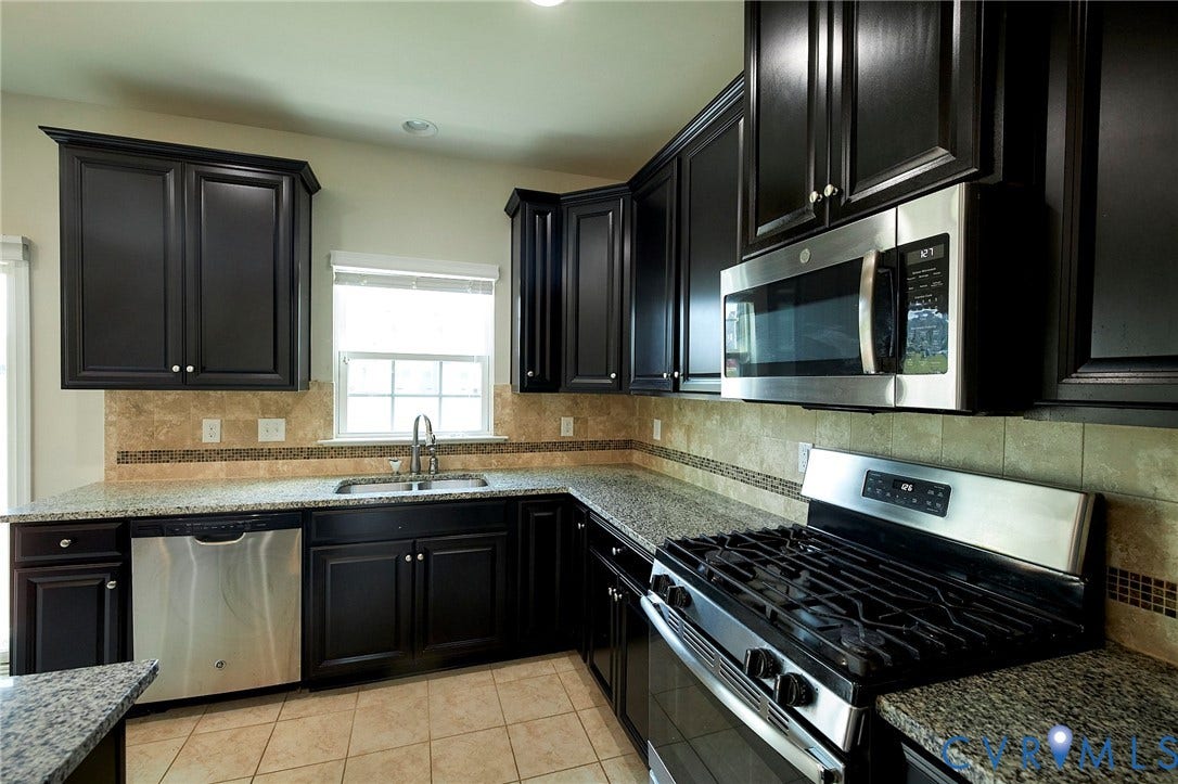 4535 Paxton Glen Court, 3W120, Glen Allen, VA 23059 Kitchen featuring dark wood cabinetry, stainless steel appliances, speckled stone countertops, and a tiled backsplash