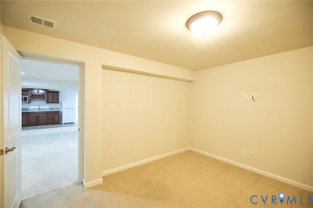 4535 Paxton Glen Court, 3W120, Glen Allen, VA 23059 Carpeted room with neutral wall paint and overhead flush-mount lighting, featuring a doorway opening to an additional room with a wet bar