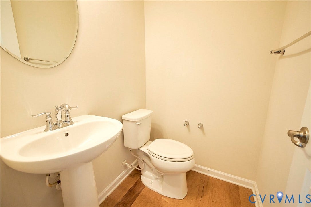 4535 Paxton Glen Court, 3W120, Glen Allen, VA 23059 Bathroom featuring a pedestal sink with a chrome faucet, round wall mirror, and wood-finish flooring