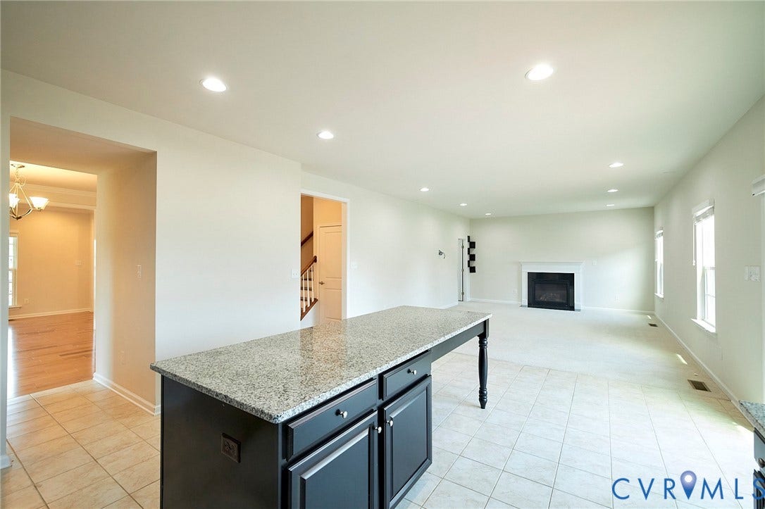 4535 Paxton Glen Court, 3W120, Glen Allen, VA 23059 Kitchen island featuring a granite countertop, dark cabinetry, and integrated electrical outlet