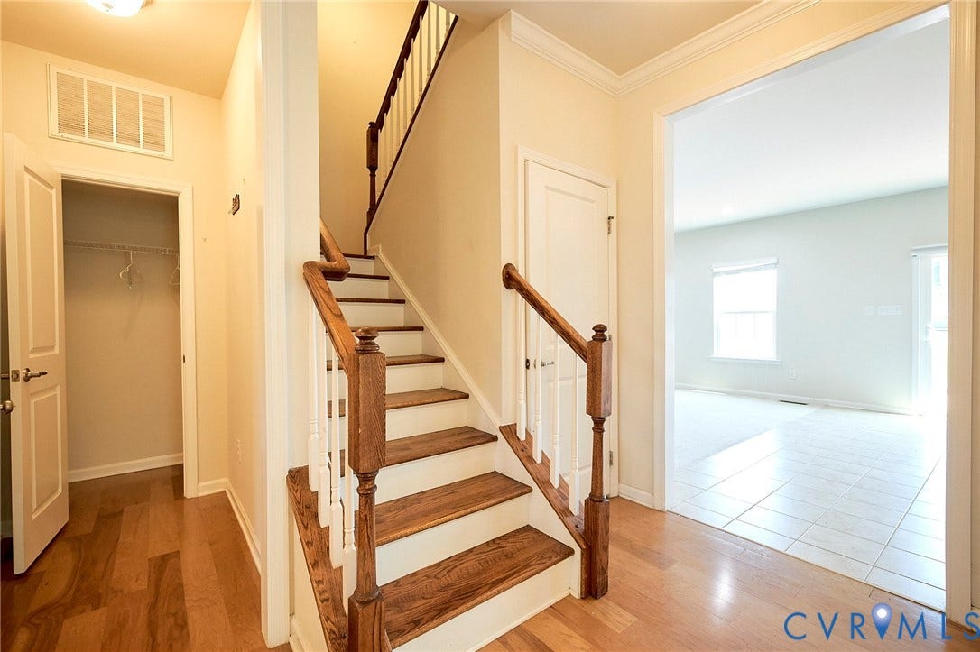 4535 Paxton Glen Court, 3W120, Glen Allen, VA 23059 Entryway featuring a wood-finish staircase with white risers, wood-finish flooring, a coat closet, and a doorway to a tiled living area with windows