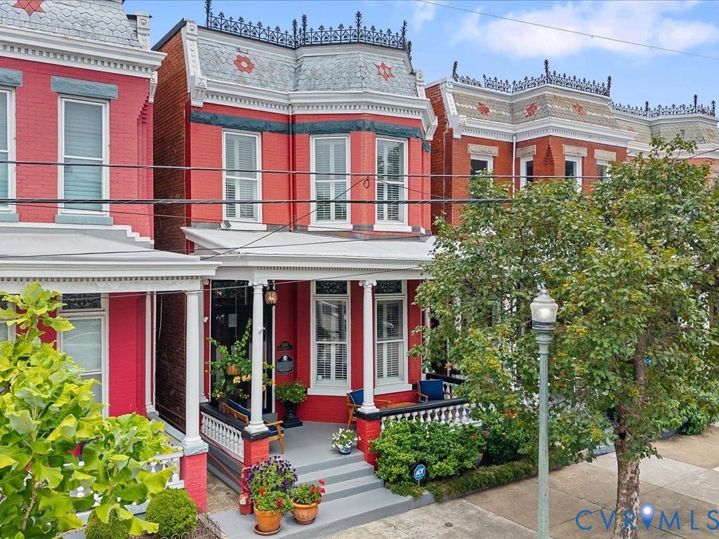 3108 E Broad Street, St John's Historic, Richmond, VA 23223 Victorian-style red brick facade with a prominent bay window, ornate roofline detailing, a covered front porch with white columns, and a gray concrete walkway