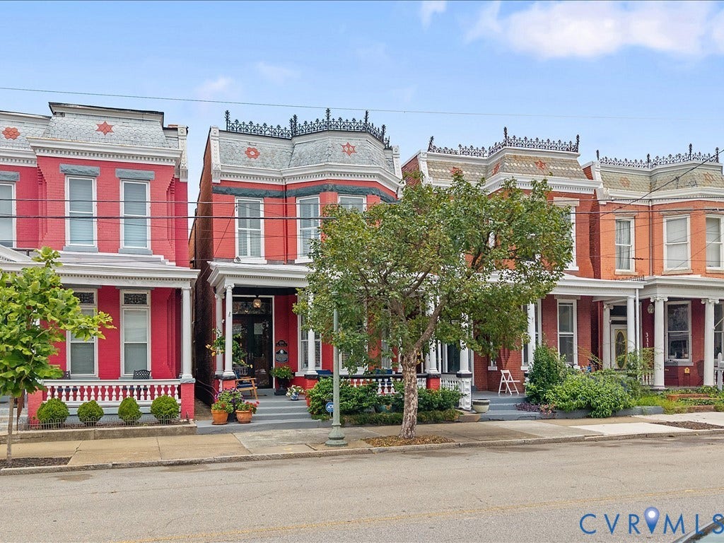 3108 E Broad Street, St John's Historic, Richmond, VA 23223 Ornate row house exterior featuring a red brick facade, white trim, a decorative mansard roof, and a covered front porch with white columns