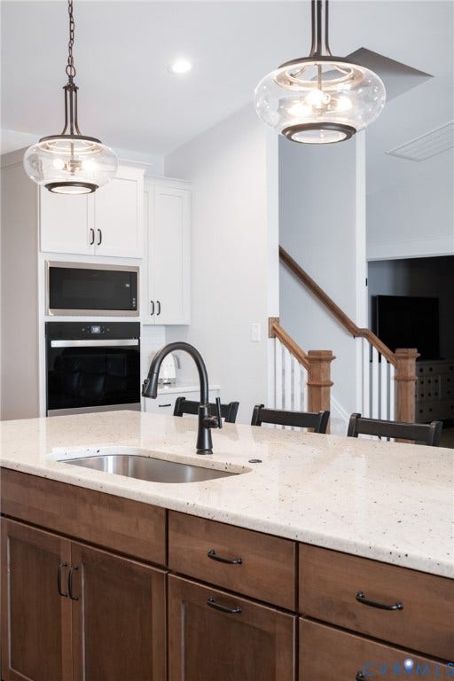 10508 Goosecross Way, Stag's Leap/ Stag's Trail, Hanover, VA 23116 Kitchen island featuring a built-in stainless steel sink, a matte black gooseneck faucet, light-toned countertop, and dark wood-finish cabinetry