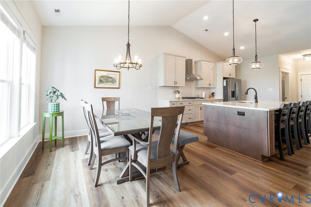 10508 Goosecross Way, Stag's Leap/ Stag's Trail, Hanover, VA 23116 Vaulted ceiling kitchen and dining area featuring wood-finish flooring, white cabinetry, a large kitchen island with seating, and stainless steel appliances