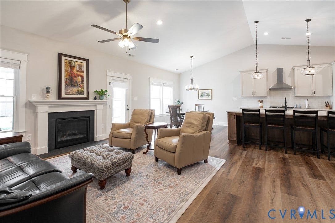10508 Goosecross Way, Stag's Leap/ Stag's Trail, Hanover, VA 23116 Spacious open-concept living area featuring vaulted ceilings, wood-finish flooring, a contemporary kitchen with pendant lighting, a white subway tile backsplash, and a fireplace with a white mantel