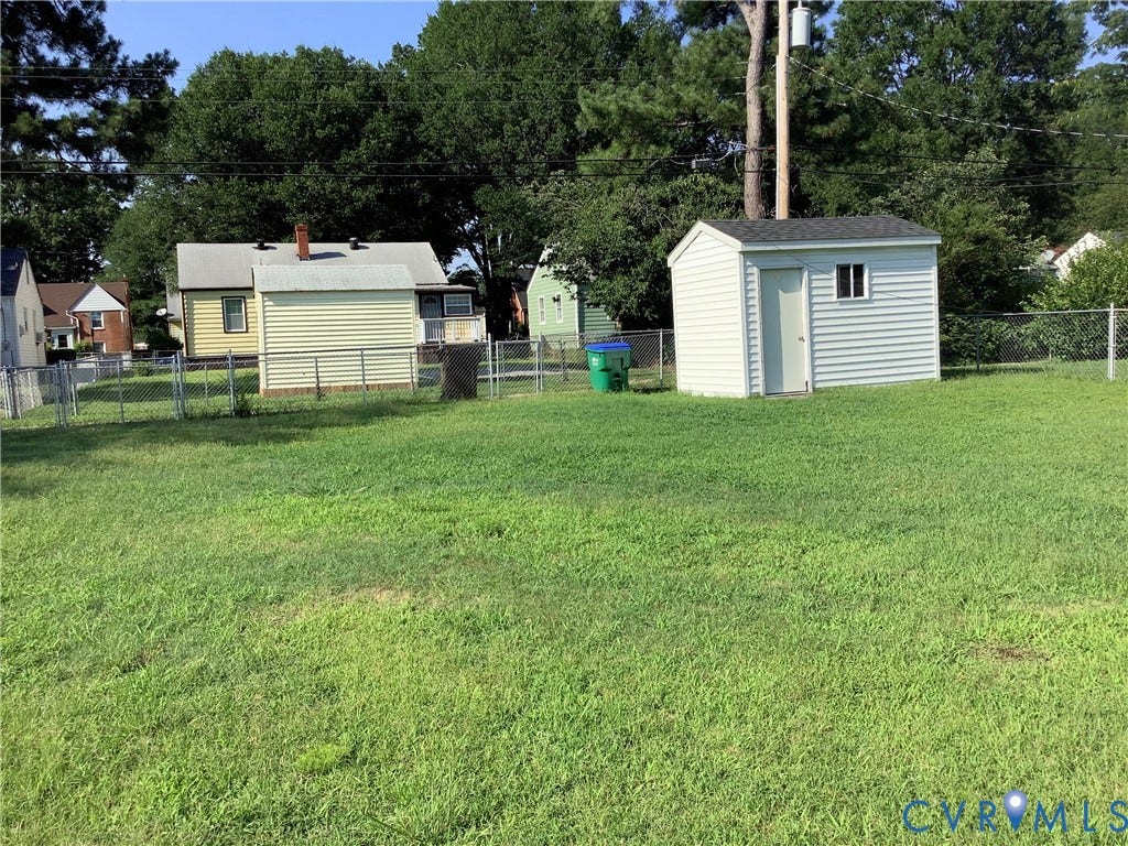 1014 Crafton Lane, Green Park, Richmond, VA 23222 Expansive grassy yard featuring a chain-link fence, a small storage shed with white siding and a window