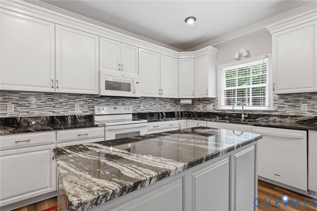 12124 Glen Kilchurn Drive, Chesterfield, VA 23838 Kitchen featuring a large central island with a polished countertop, white cabinetry with crown molding, a mosaic tile backsplash, and dark patterned countertops