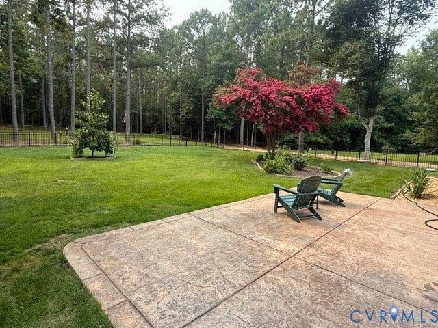 12124 Glen Kilchurn Drive, Chesterfield, VA 23838 Expansive backyard featuring a stamped concrete patio, manicured lawn, and mature trees providing natural privacy