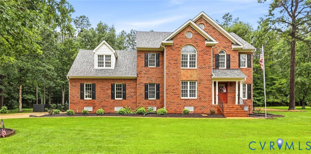 12124 Glen Kilchurn Drive, Chesterfield, VA 23838 Brick exterior residence featuring a prominent arched window, dormer details, a covered front entry, dark shutters, and a spacious lawn
