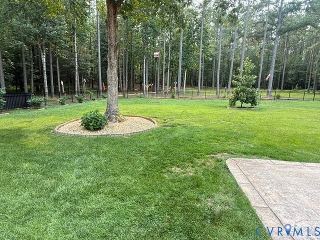 12124 Glen Kilchurn Drive, Chesterfield, VA 23838 Expansive fenced yard featuring mature trees, green lawn, and a stamped concrete patio