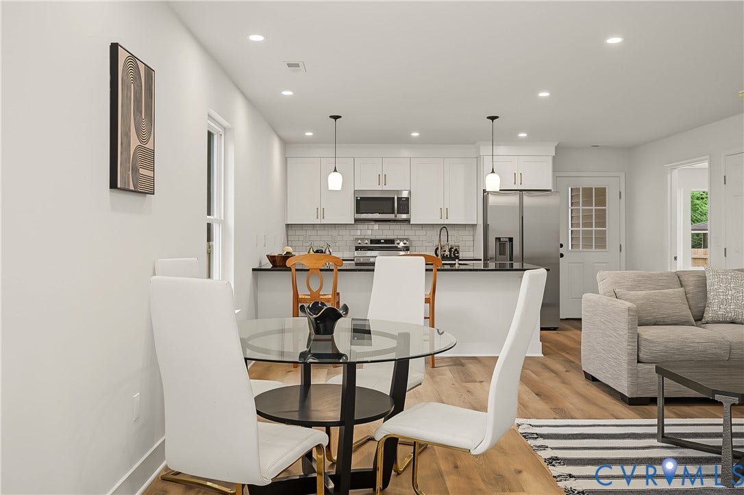 Open-concept living space featuring wood-finish flooring, recessed lighting, and a kitchen with white cabinetry and stainless steel appliances