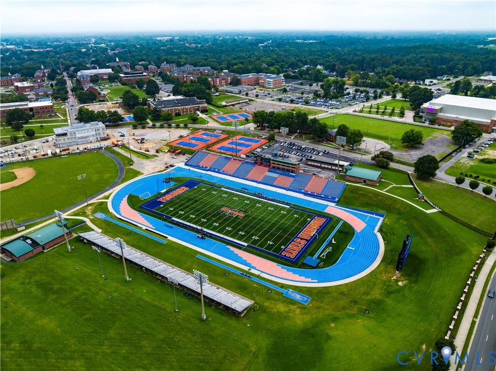 Aerial perspective showcasing a sports complex with a prominent blue track and green athletic field