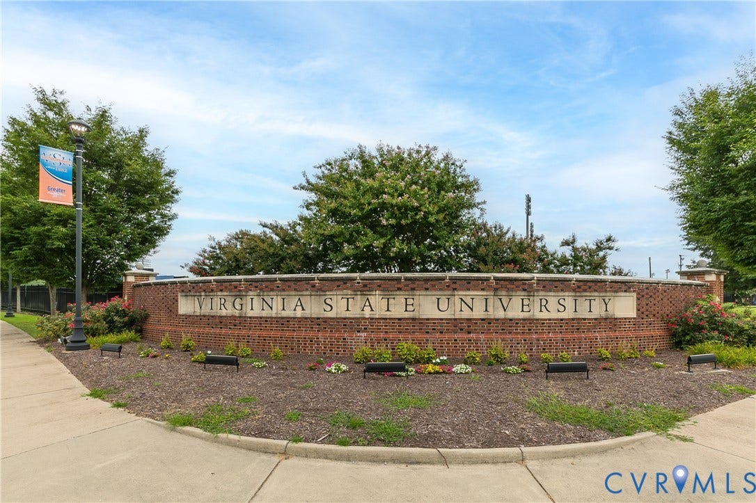 Virginia State University's distinctive brick entrance monument, featuring carved institutional signage and framed by mature landscaping, manicured planting beds, and complementary hardscaping