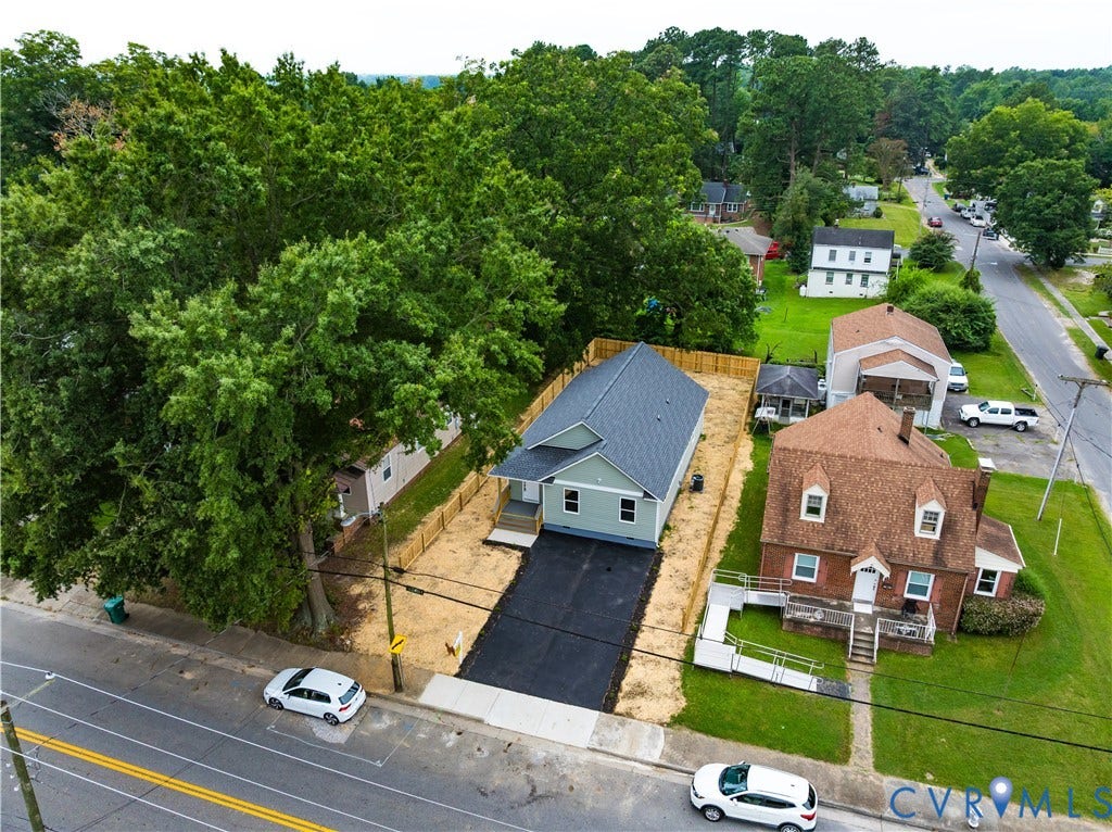 Newly constructed home situated on a generous lot featuring a modern architectural design with a dark-pitched roof, fresh asphalt driveway, and mature landscaping with established trees