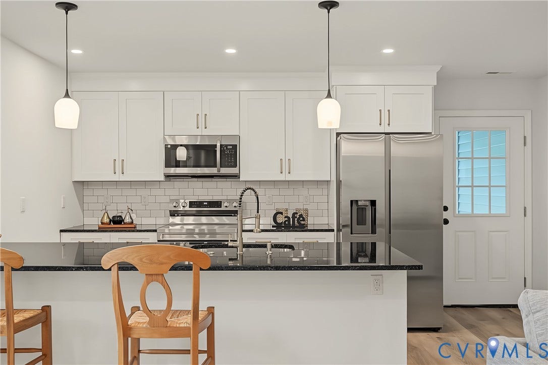 Modern kitchen featuring white cabinetry with brushed nickel hardware, subway tile backsplash, and stainless steel appliances including a French-door refrigerator with ice and water dispenser