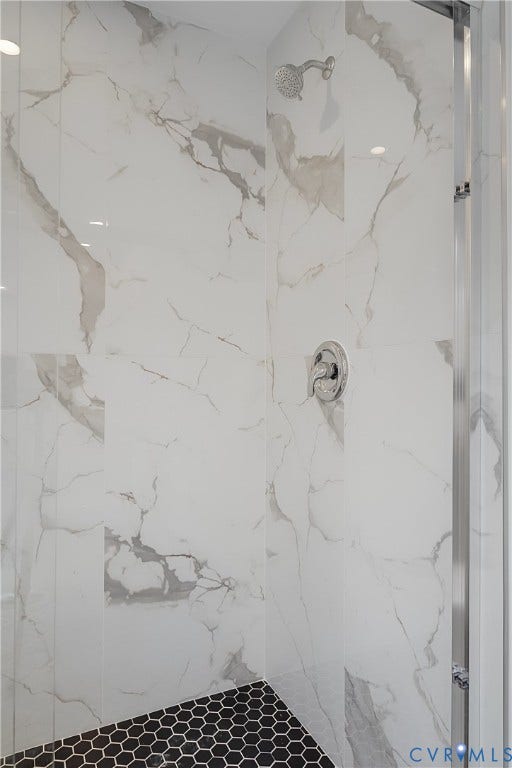 Shower enclosure featuring white marble-look wall tiling with gray veining