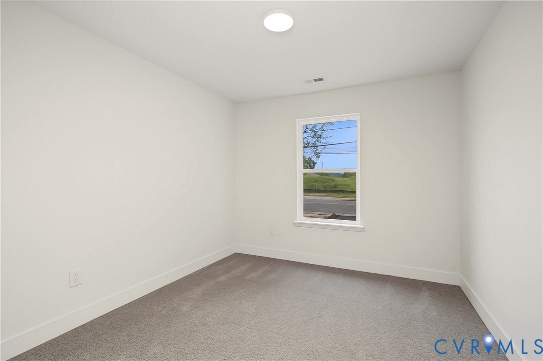 Neutral wall finishes throughout this room, featuring a single window, recessed lighting, and carpeted flooring