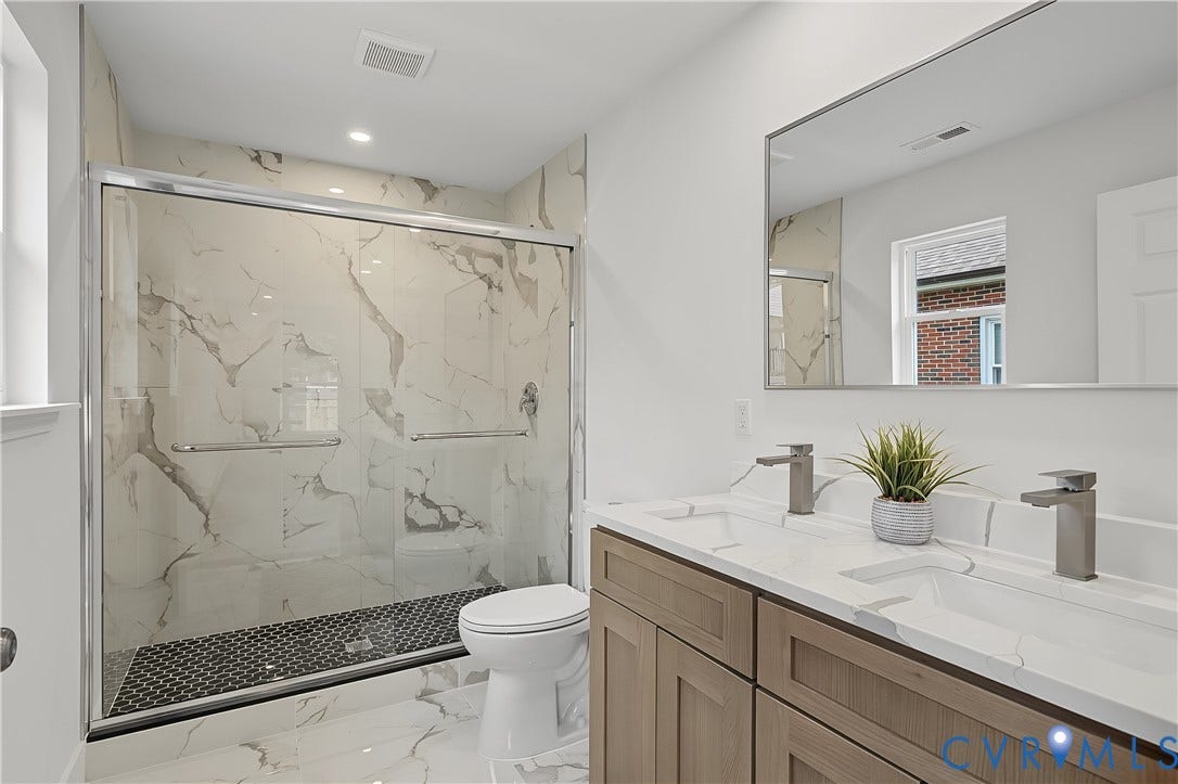 Double vanity featuring integrated sinks and brushed nickel faucets, set against a full-width mirror