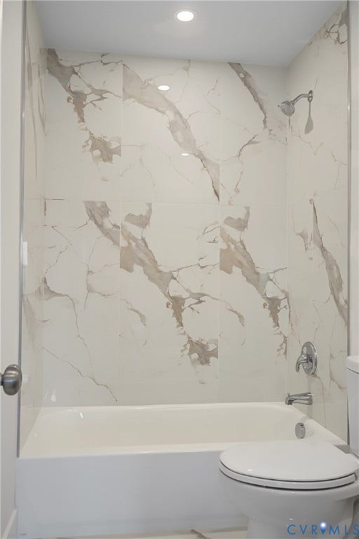Bathtub with white subway tile surround featuring grey veining, chrome fixtures, and recessed lighting
