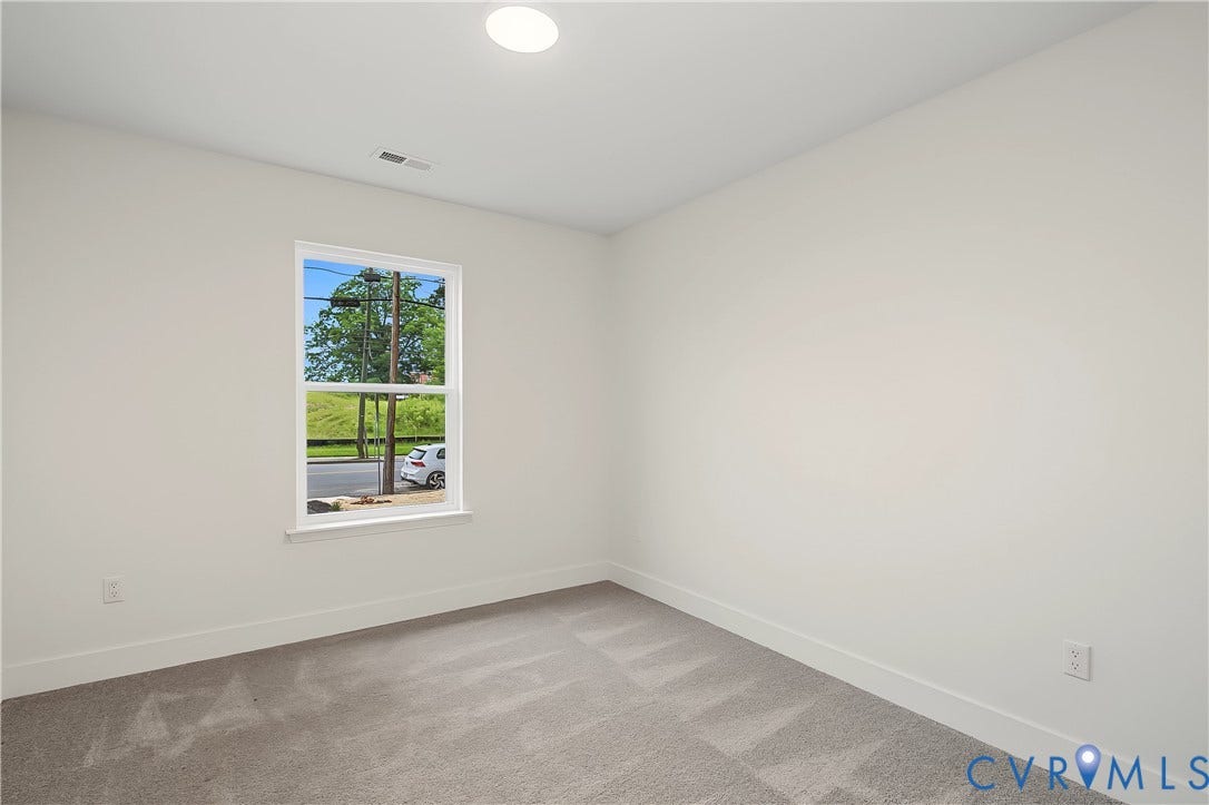 Room featuring light gray carpet flooring, white walls, and a single window with white trim