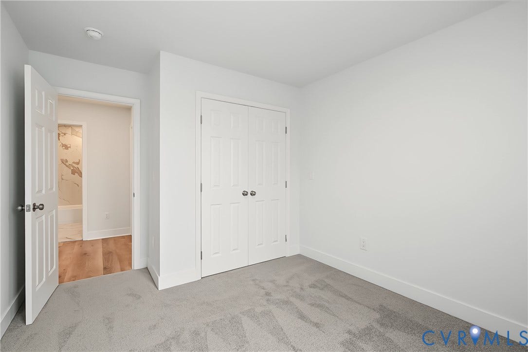 Room with light gray carpeting, white walls, and a white bi-fold closet door