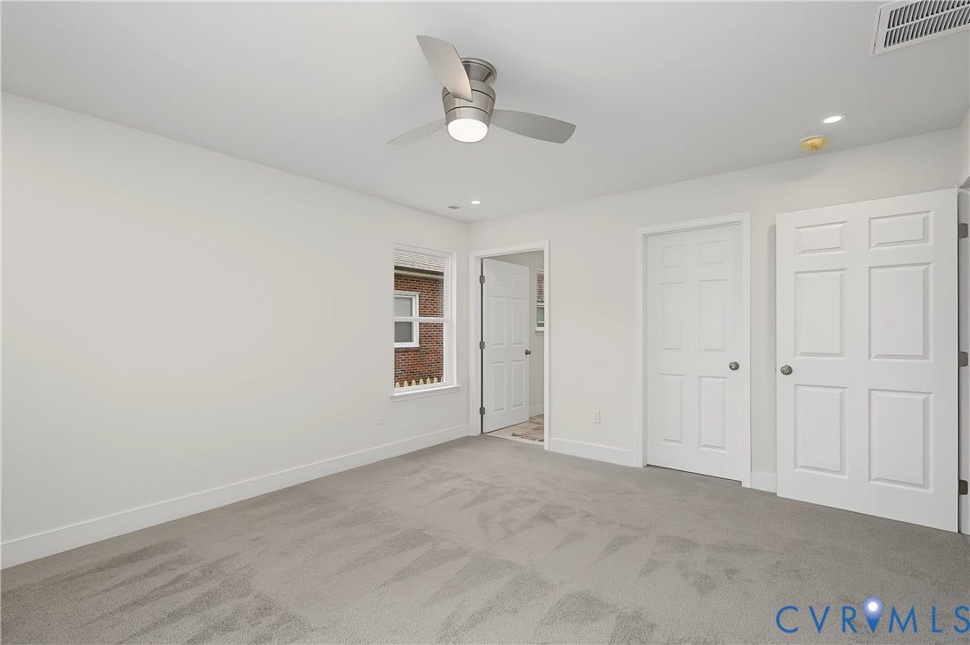 Spacious bedroom with neutral wall finishes, plush carpeting, and abundant natural light from recessed ceiling fixtures