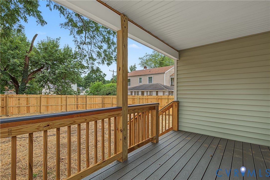Spacious composite deck featuring freshly finished wood railings with vertical balusters, composite decking boards, and a covered pavilion structure with white ceiling