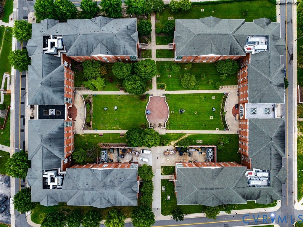 Courtyard property featuring multiple brick buildings with gray shingle roofs, surrounding a central green space