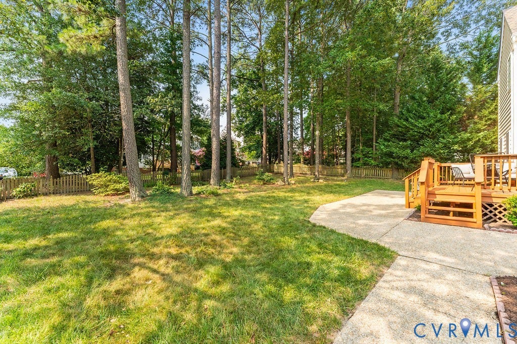 5316 Lemoore Drive, Glen Allen, VA 23059 Expansive backyard featuring a natural wood deck with railings, a concrete patio, a privacy fence, and mature trees