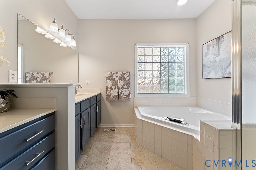 5316 Lemoore Drive, Glen Allen, VA 23059 Deep soaking tub with tile surround, glass block window, double vanity with gray cabinetry, and tile flooring