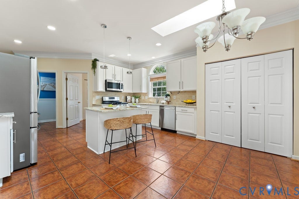5316 Lemoore Drive, Glen Allen, VA 23059 Kitchen featuring a central island with countertop seating, white cabinetry, stainless steel appliances, and a tiled floor