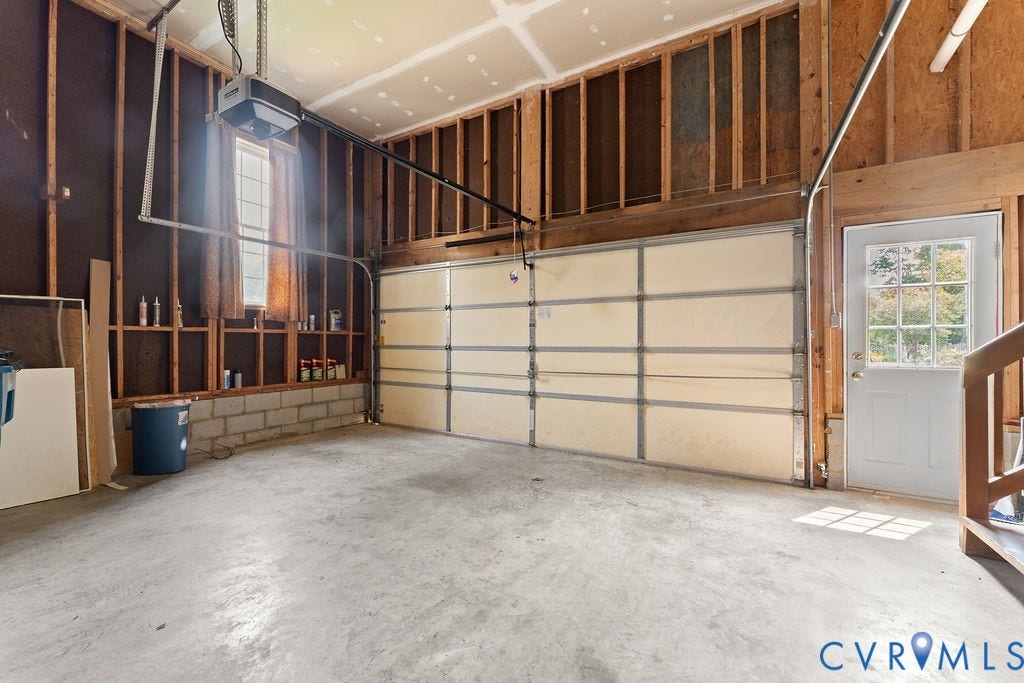 5316 Lemoore Drive, Glen Allen, VA 23059 Spacious garage featuring concrete flooring, a single garage door, a window with natural light, a side entry door with window panes, and exposed wood framing