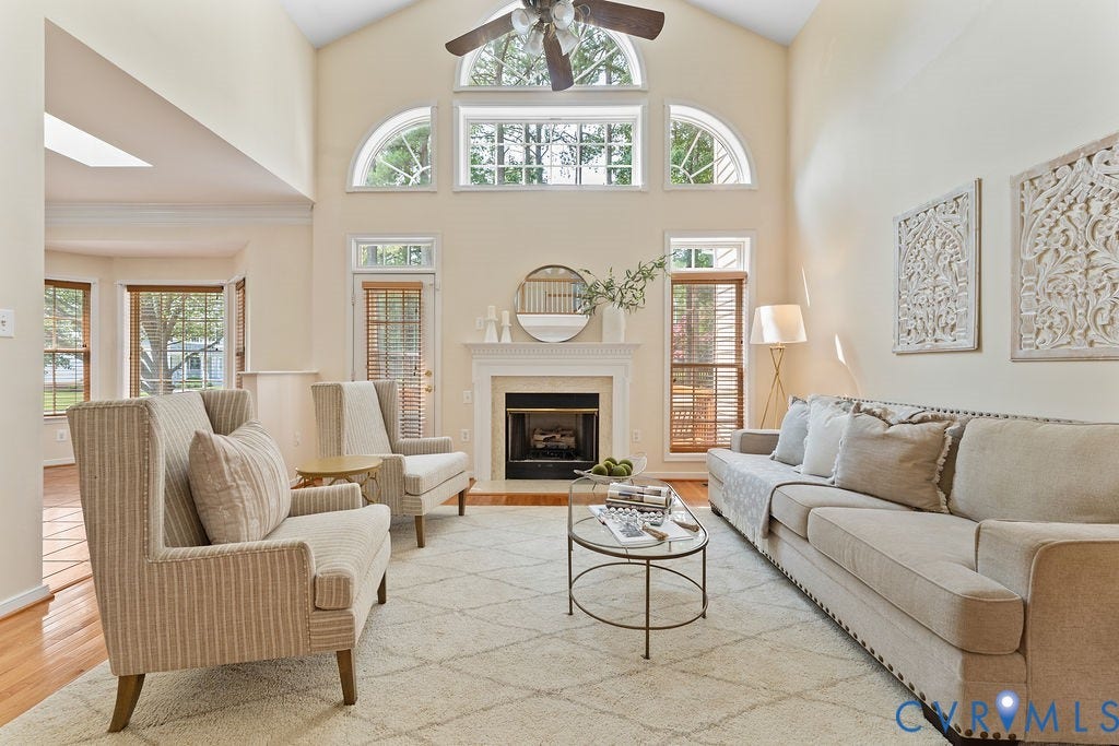 5316 Lemoore Drive, Glen Allen, VA 23059 Vaulted ceiling featuring a ceiling fan, a fireplace with a white mantel, and extensive natural light through multiple windows, including arched transom windows