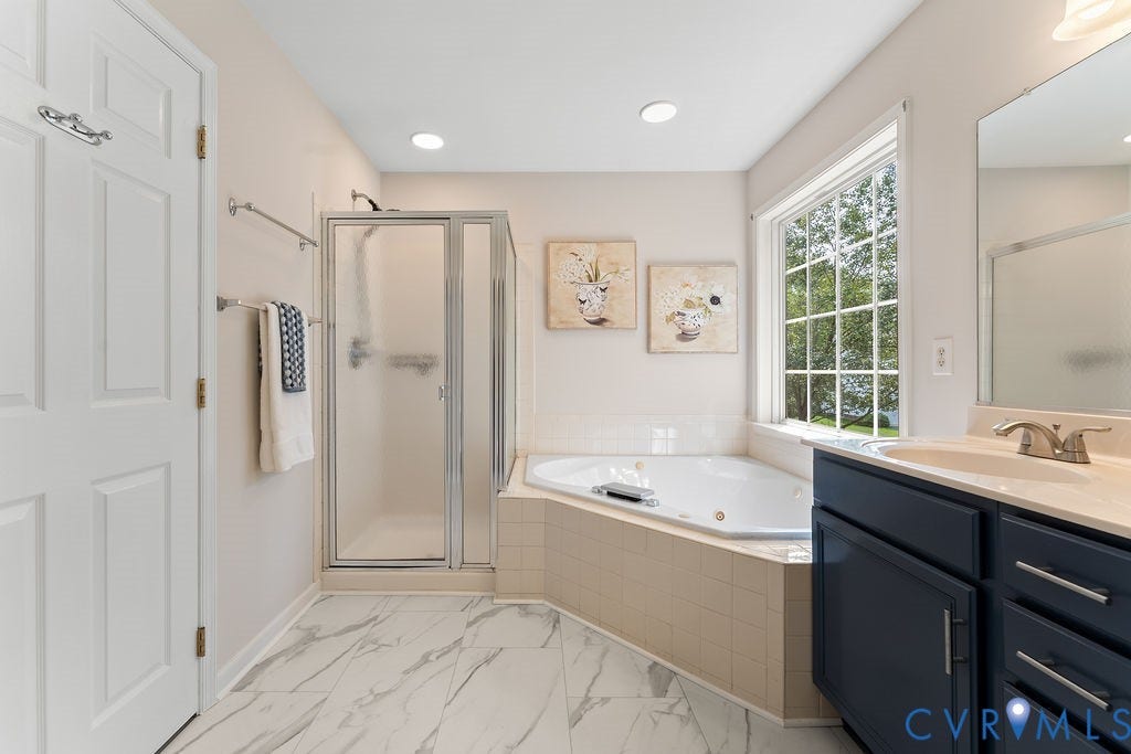 5316 Lemoore Drive, Glen Allen, VA 23059 Bathroom featuring a corner jetted soaking tub, a glass-enclosed shower, and a single vanity with a dark blue cabinet