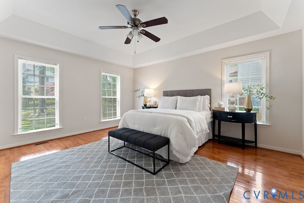 5316 Lemoore Drive, Glen Allen, VA 23059 Bright bedroom featuring a tray ceiling with a ceiling fan, dual large windows, and warm wood-finish flooring
